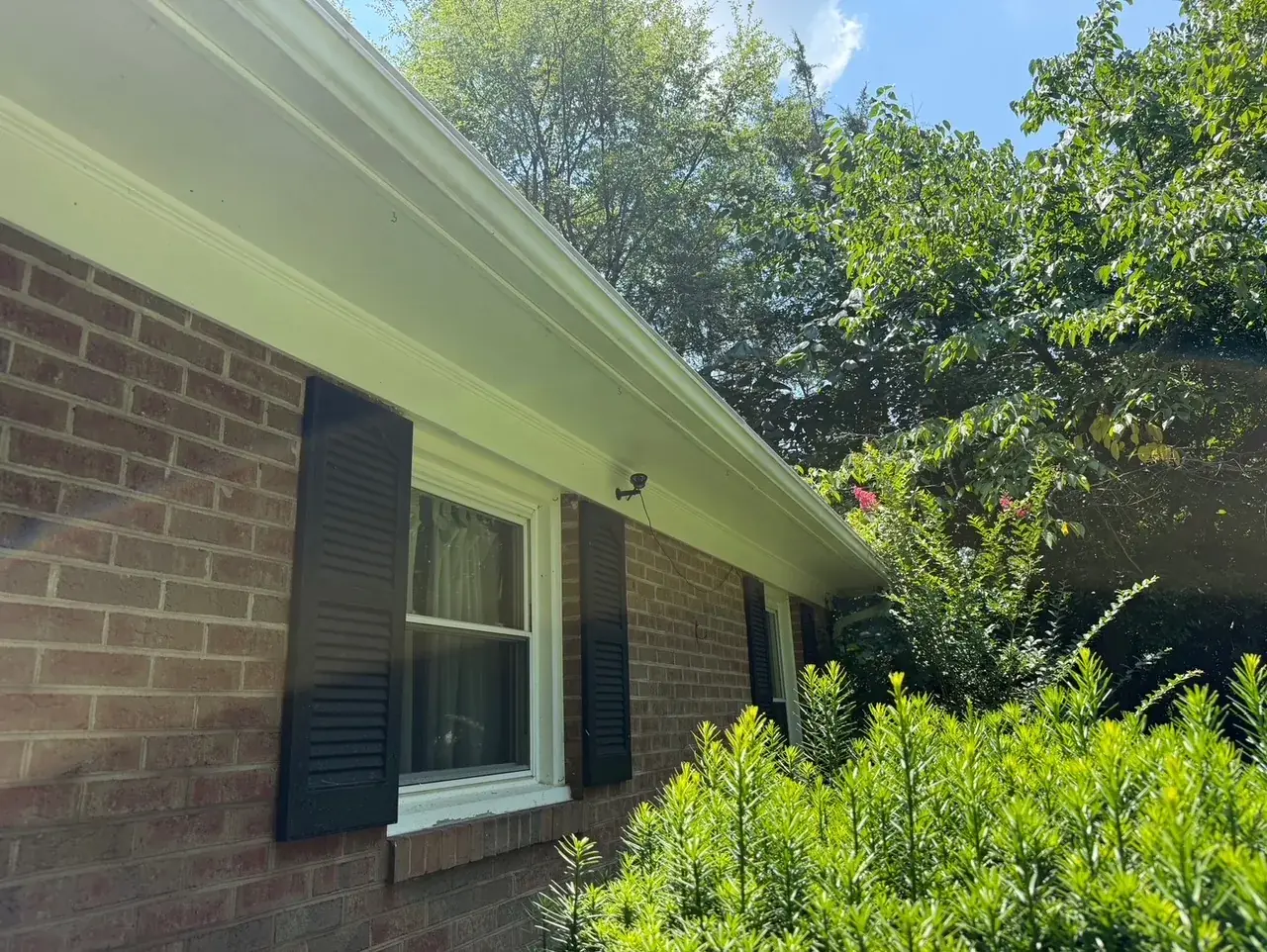 Clean brick home with white gutters after pressure washing
